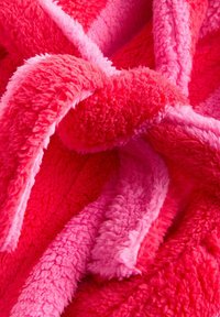 Fleece blanket in vibrant pink and lighter pink. Features soft, fluffy texture with varying thickness and intertwined layers.