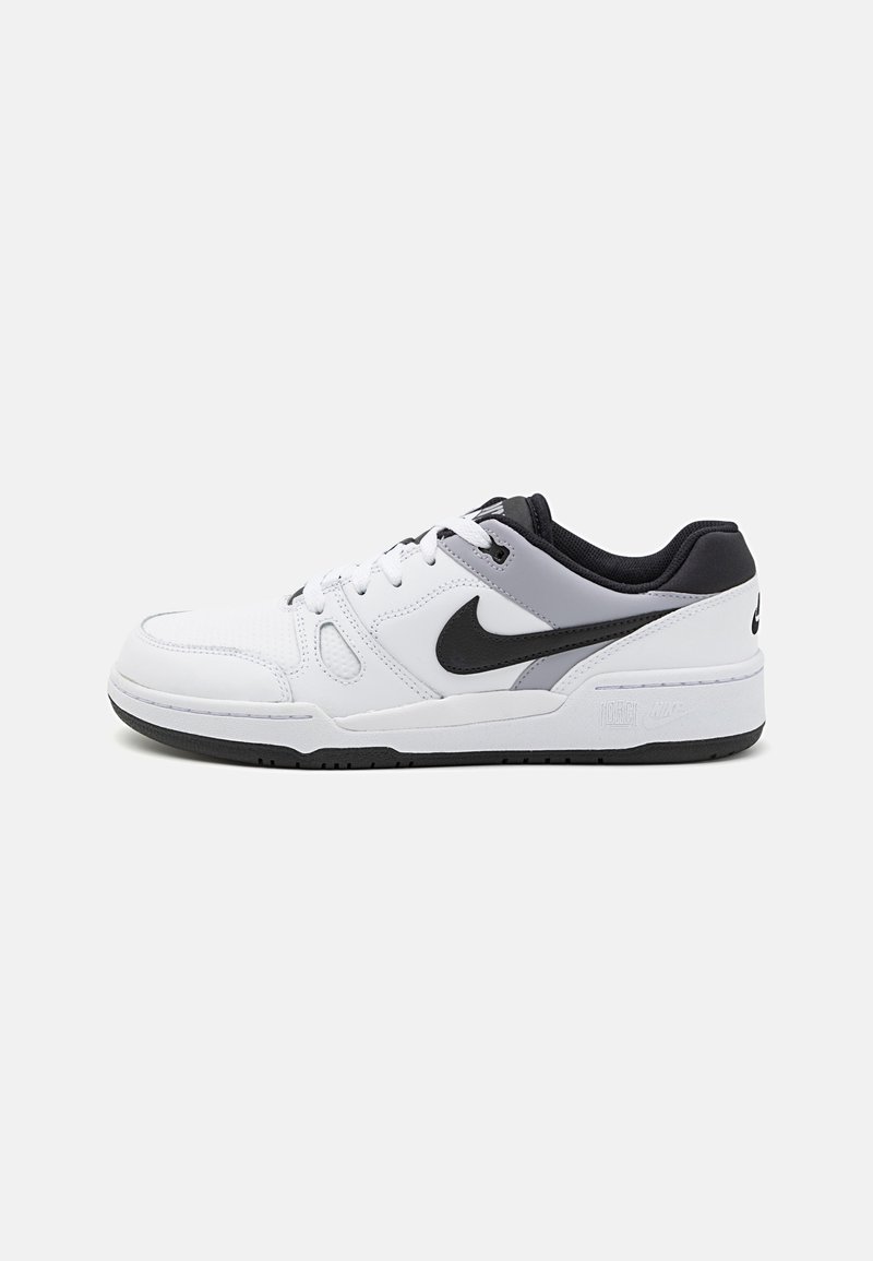 Baskets basses blanches Nike avec logo Swoosh noir, accents noirs et gris, lacets blancs et semelle noire, vues de côté sur un fond uni.