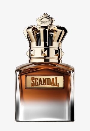 Amber perfume bottle labeled "Scandal" with a gold crown-shaped cap and a sun emblem on top.