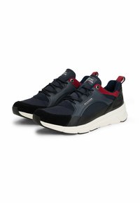Un paio di sneakers Tommy Hilfiger di colore blu navy, nero e rosso con suole bianche e design con lacci su uno sfondo bianco.
