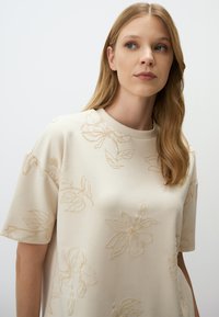 Crème kleurige sweatshirt met verhoogde bloemenborduursels in lichtbeige, korte mouwen, een ronde halslijn en een relaxte pasvorm.