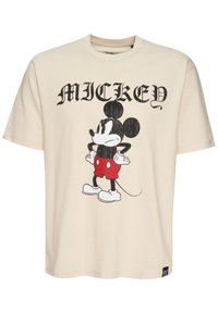 Camiseta de algodón color crema con un gráfico en blanco y negro de Mickey Mouse con pantalones cortos rojos y zapatos blancos, escote redondo y mangas cortas.