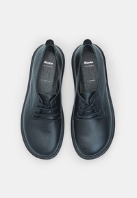 Sorte lædersko med en glat tekstur, snørebåndsdesign og rund tå. Har brandlogo og indlægssåler mærket "HELE LÆDER."