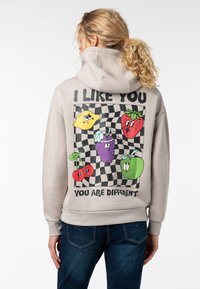 Lichtgrijze hoodie met een grafisch ontwerp van kleurrijke cartoonfruit op een geruite achtergrond en de tekst: "IK VIND JE LEUK JE BENT VERSCHILLEND."