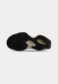 Semelle de chaussure avec motif ondulé noir, intermédiaire beige et sections découpées pour la flexibilité et l'adhérence.