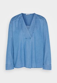 Blouse en denim bleu clair à manches longues avec un col en V profond sans boutons, présentant des détails cousus sur les épaules et les poignets.
