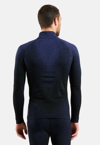 Long-sleeve navy thermal shirt with textured ribbed pattern, standing collar, and fitted design, worn by a man, showing back view.