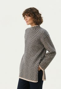 Sweter dzianinowy z wysokim kołnierzem, wzorem w jodełkę w odcieniach beżu i granatu, z bocznymi kieszeniami, o luźnym kroju i długich rękawach.
