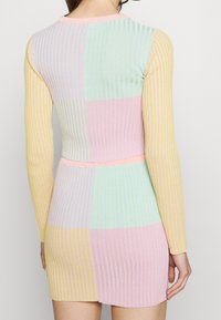 Geribbelde gebreide jurk met lange mouwen, een aansluitend lijfje en een kleurblokontwerp in pasteltinten van roze, groen, geel en blauw.