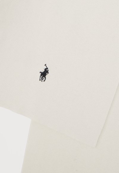 Μαύρο κεντημένο λογότυπο παίκτη πόλο σε φόντο από μάλλινο ύφασμα εκρού χρώματος.