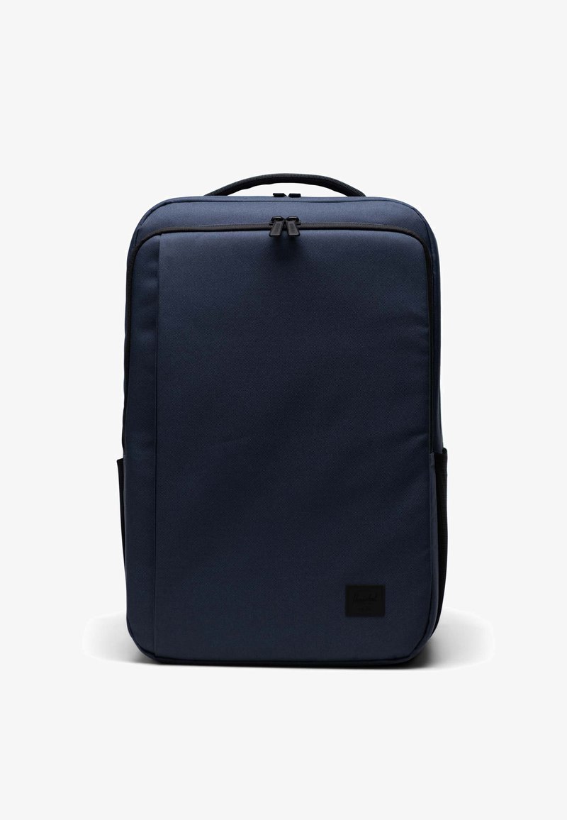 Mörkblå ryggsäck tillverkad av slitstarkt tyg, med en elegant rektangulär design, bärhandtag och två sidofickor. Innehåller dragkedjestängning.