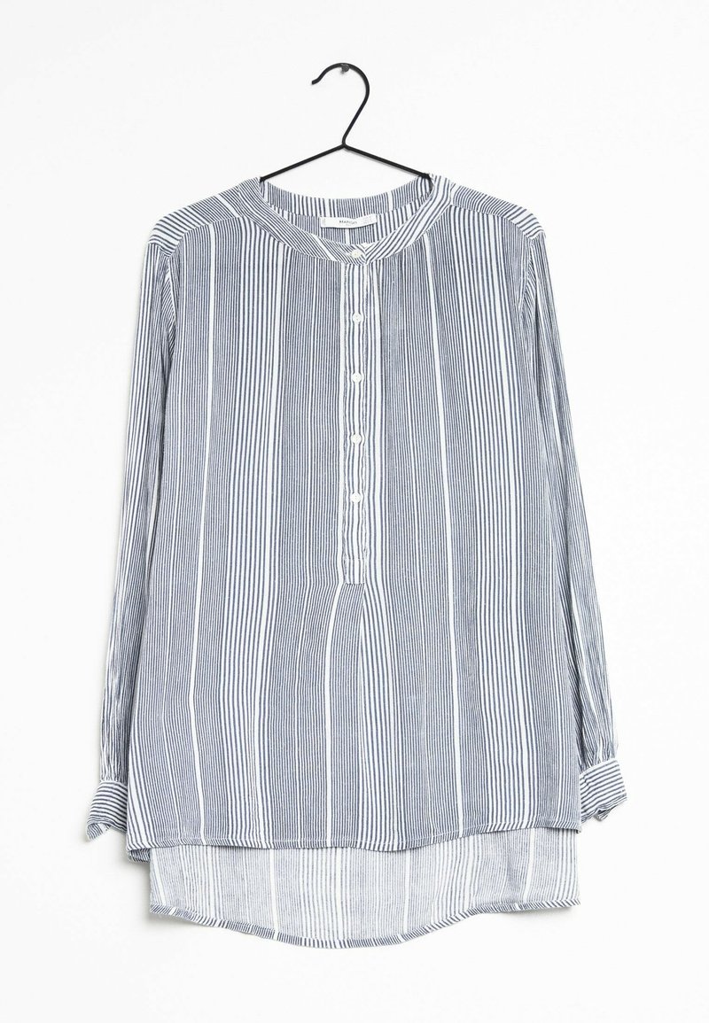 Chemise à manches longues boutonnée avec des rayures verticales blanches et noires, col rond, suspendue sur un cintre noir sur fond blanc.