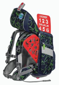 Mochila con un patrón geométrico negro y verde, plantillas rojas para letras y números, correas ajustables grises y una insignia circular azul.