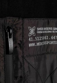 Tessuto nero con una tasca con zip nera. Testo stampato bianco che include il nome del marchio e i dettagli di contatto. Superficie texturizzata.