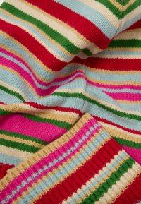 Adītā džemperis ar horizontālām svītrām sarkanā, rozā, zaļā, krēma un gaiši zilā krāsā. Strukturētas ribu malas, mīksts vilnas maisījuma materiāls.