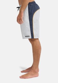 Ανδρικά μαγιό σε άσπρο και ναυτικό μπλε, με πλαϊνή επένδυση και κίτρινη ραφή. Ελαφρύ ύφασμα με ελαστική μέση και κορδόνι.