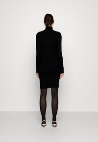 Svart rullkrageklänning med lång ärm, knälång nederdel, bärs med svarta strumpbyxor och nude klackskor, minimalistisk design.