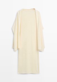 Lang cardigan i cremefarve med åben front og brede ærmer, vist fladt mod en hvid baggrund.