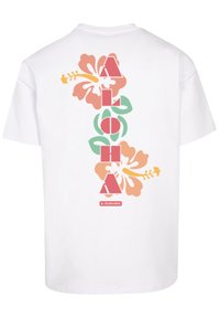 White cotton t-shirt featuring a vertical design with the text "ALOHA" and colorful hibiscus flowers in pink, orange, and green.