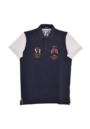 Polo di colore blu navy con maniche corte bianche, dotato di vari patch ricamati e un piccolo accento giallo all'orlo.