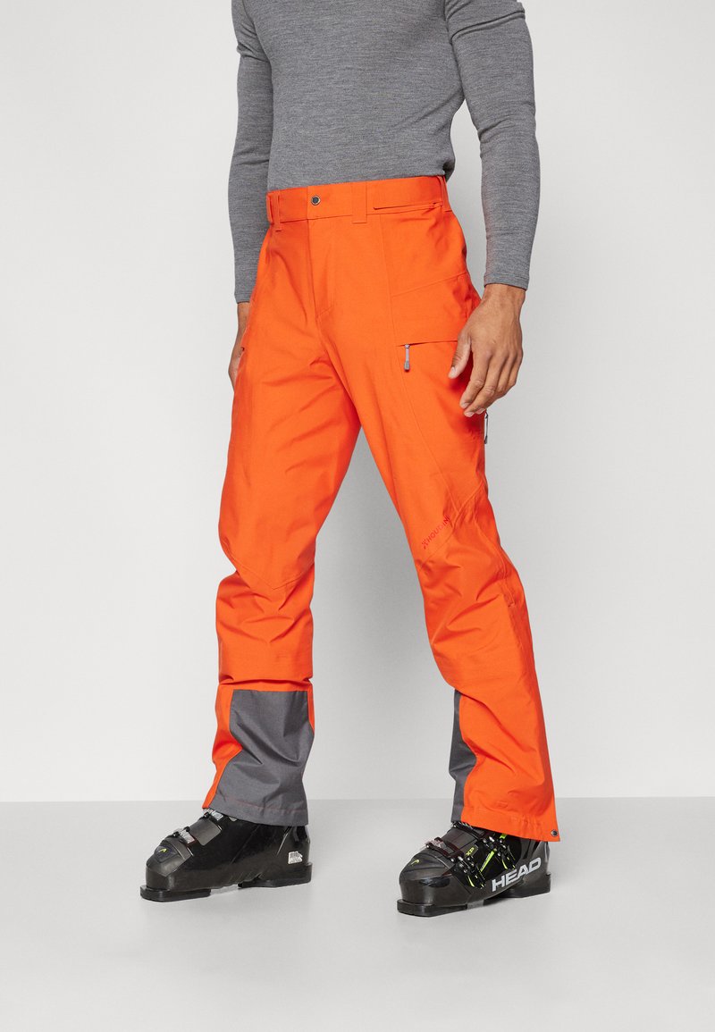 Helle orange Skihosen mit grauen Unterschenkeln, aus wasserdichtem Material gefertigt. Verfügt über Cargo-Taschen und einen taillierten Bund.