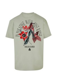 Světle zelené bavlněné tričko s květinovým grafickým potiskem v červené a černé barvě s textem "V RÁJI S JUST RINSE" a "NEKONEČNÉ LÉTO."