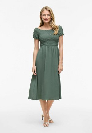 Robe midi verte avec un bustier smocké, des manches courtes bouffantes et une jupe fluide. Fabriquée en tissu léger avec une texture subtile.