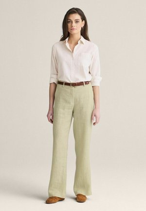 Lyserød button-up skjorte med opfoldede ærmer, beige linnedbukser, brun læderbælte og brune ruskindsko. Enkel design og afslappet pasform.