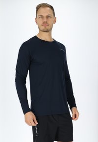 Navyblaues Sportshirt mit langen Ärmeln, Rundhalsausschnitt und taillierter Passform, aus leichtem Material gefertigt. Verfügt über ein dezentes Logo auf der Brust.