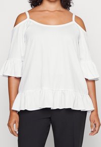 Top bianco con design a spalle scoperte, maniche a volant e orlo smerlato. Realizzato in tessuto testurizzato, presenta una vestibilità comoda.