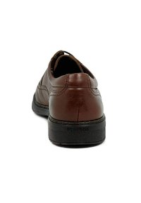 Zapato de cuero marrón con la parte trasera redondeada, superficie texturizada y suela de goma negra. Presenta detalles de costura y un logo en la suela.