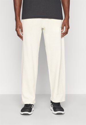 Brīvi pieguļoši, baltie auduma bikses ar smalku režģa rakstu, apvienoti ar melnām sporta apaviem. Piemēroti ikdienas apģērbam.