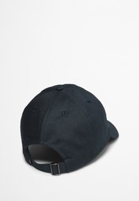 Dark blue cotton cap with a curved brim, adjustable metal buckle, and ventilation holes on the top for breathability.