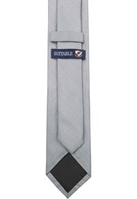 Grijze stropdas met een gestructureerd patroon, slanke vorm en een marineblauwe label met de tekst "SUITABLE." De achterkant is effen zwart.