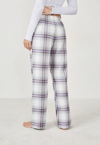 Geruite pyjamabroek met een paars en blauw patroon op een witte achtergrond, gemaakt van een zachte stof met een elastische tailleband.