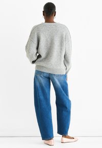 Gray knitted sweater with small pink and white patterns, wide sleeves, loose fit, paired with high-waisted blue jeans and light pink flats.