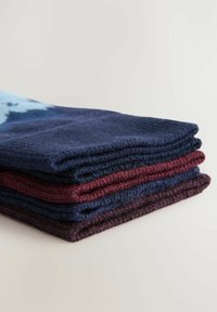 Une pile de quatre serviettes en coton tricoté de couleur bleu marine foncé et bourgogne. Caractéristiques d'un tissu texturé avec des bords étroitement tissés, soigneusement pliées.