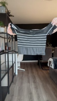 Čierny krátky rukáv top s horizontálnymi bielymi pruhmi. Má voľný strih a jednofarebný čierny spodok. Vyrobené z mäkkého textilu, s ľahkou textúrou.