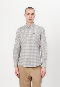 Chemise à boutons dans un motif à carreaux léger gris et foncé, en coton. Elle a un col pointu et des manches longues.