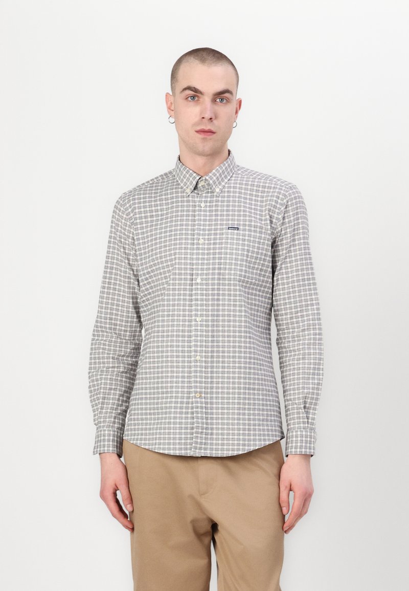 Chemise à boutons dans un motif à carreaux léger gris et foncé, en coton. Elle a un col pointu et des manches longues.