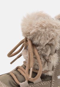 Botte d'hiver marron avec un revers en fausse fourrure et un tissu texturé. Les lacets beige et les accents en étoile enrichissent le design. Confortable, fonctionnelle et chaude.