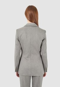 Blazer grigio a righe con vestibilità su misura, colletto a revers e polsini con bottone. Vista posteriore che mostra un design delle spalle strutturato e una silhouette elegante.