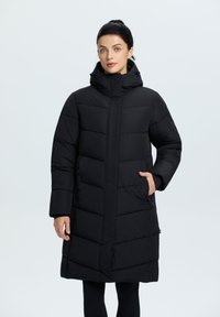 Sort polstret lang frakke med høj krave, der har lynlåslukning, sidelommer og en quiltet tekstur. Glat materiale med et elegant design.