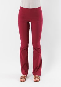 Pantaloni rossi elasticizzati con una vestibilità aderente in vita e gambali a zampa. Il tessuto è liscio, senza motivi visibili o decorazioni.