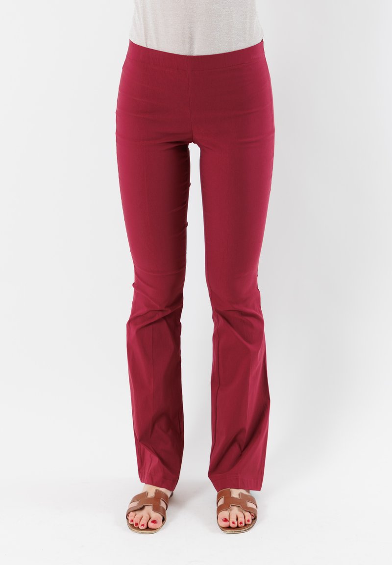 Pantaloni rossi elasticizzati con una vestibilità aderente in vita e gambali a zampa. Il tessuto è liscio, senza motivi visibili o decorazioni.