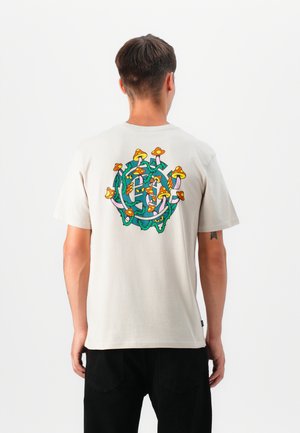 Hellbeige Baumwoll-T-Shirt mit einem bunten Pilzdesign auf dem Rücken. Kurzärmelig mit lockerer Passform und ohne sichtbare Logos.