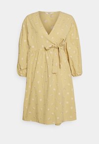 Vestido amarelo envolvente com decote em V, mangas de três quartos, bordados florais e um laço na cintura; tecido leve e fluído.