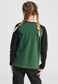 Maglietta a maniche lunghe verde e nera con maniche raglan, materiale in cotone, cuciture piatte e design a contrasto sulle spalle.