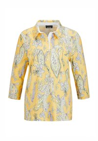 Geel shirt met een kraag en driekwartmouwen, met een bloemig paisleypatroon in paarse en groene tinten.