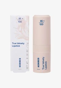 Il rossetto Korres True Velvety nella tonalità 85+, con tubo cilindrico beige accanto a una scatola di carta abbinata con testo blu e dettagli sul prodotto.